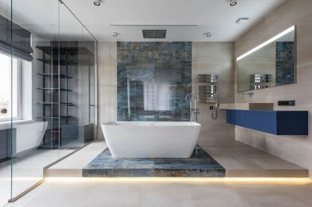 Baño grande con bañera central en tonos azules y piedra gris