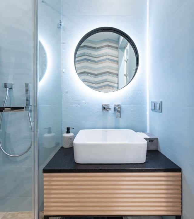 Baño pequeño con mueble en madera e iluminación LED tras el espejo