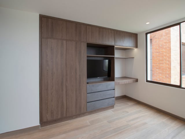 Closets funcionales, colores gris y madera con espacio para TV e iluminación LED