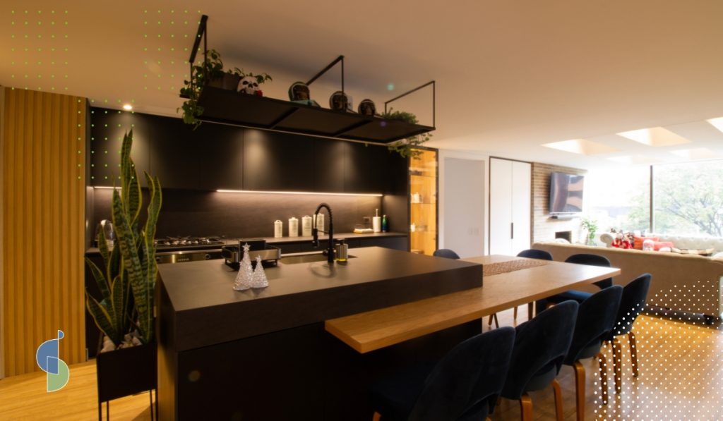 Cocina en negro mate con luz LED bajo los muebles altos y mesa integrada a la isla