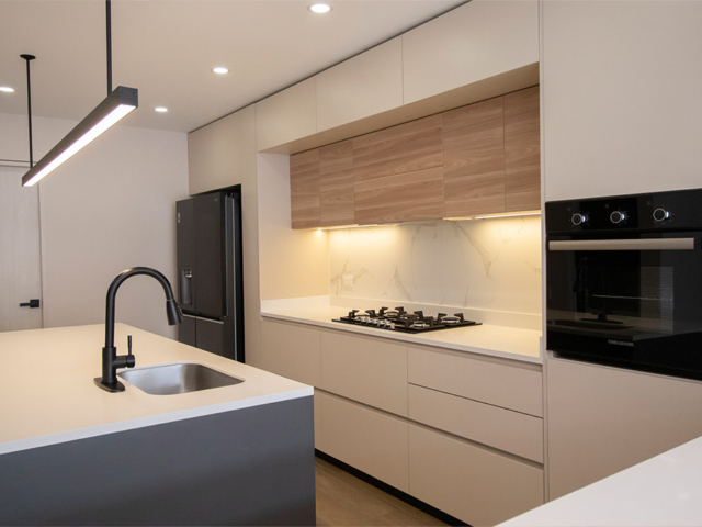 Cocina integral de melamina en tono madera con isla central y electrodomésticos integrados.