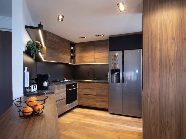 Cocina integral lujosa y moderna en madera, colores negros, iluminación LED y electrodomésticos empotrados