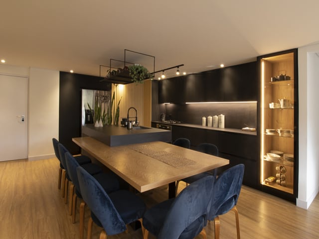 Reestructuración de cocina integral moderna con mesón Neolith, acabados en tono negro mate e implementación de paneles alistonados que brinda elegancia y confort en cada espacio.