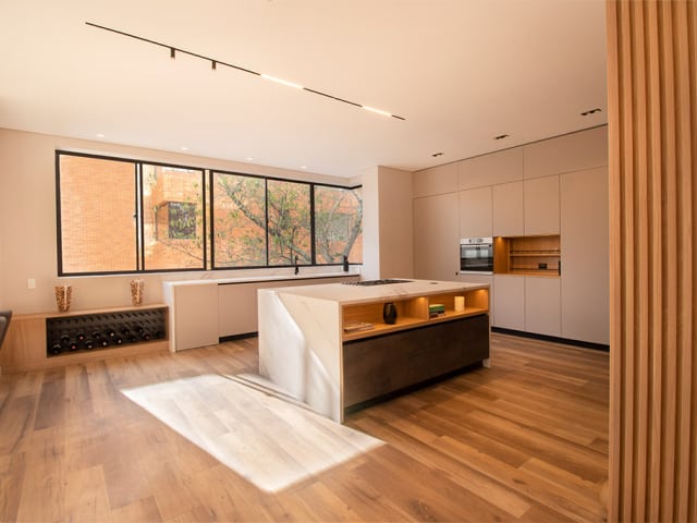 Diseño de cocina moderna con paneles alistonados y acabados de lujo con mesón en tonos claros