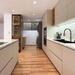 Cocina lineal en tonos greige con enchapes en madera y mesón en piedra sinterizada veteada
