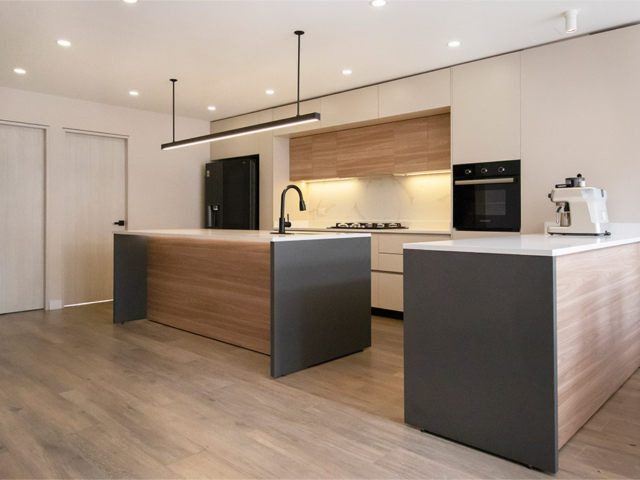 Remodelación de cocina en L de melamina en tono madera con estilo minimalista, isla central y colores claros.