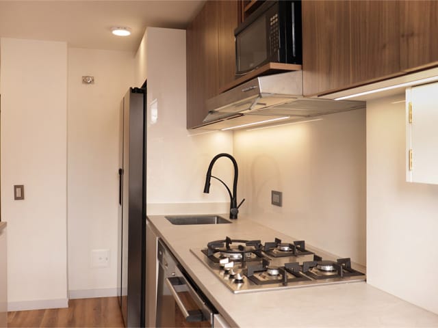 Elegante remodelación de cocina integral con meláminico novopan Gales y HPL Deklam Matt White, electrodomésticos modernos e iluminación arquitectónica.