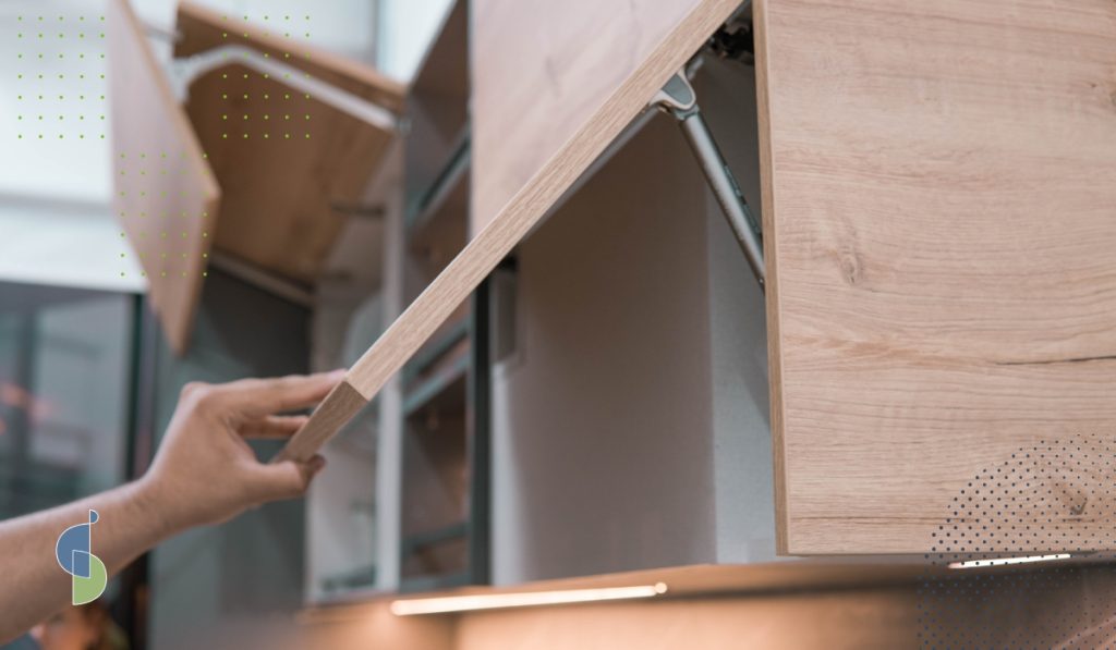 Mano abriendo una puerta elevable de mueble alto con herraje de elevación en acabado madera