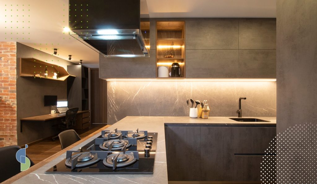 Campana extractora suspendida sobre la estufa de la isla en una cocina abierta hacia una zona de estudio