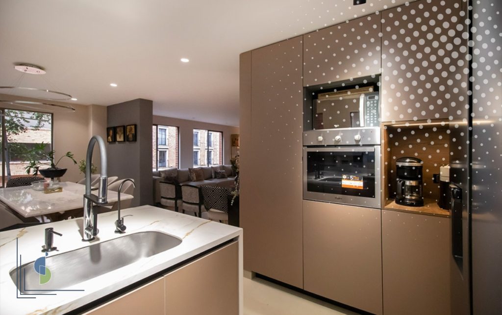 Cocina abierta con isla y lavaplatos conectada al comedor y la sala de un apartamento