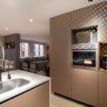 Cocina abierta con isla y lavaplatos conectada al comedor y la sala de un apartamento