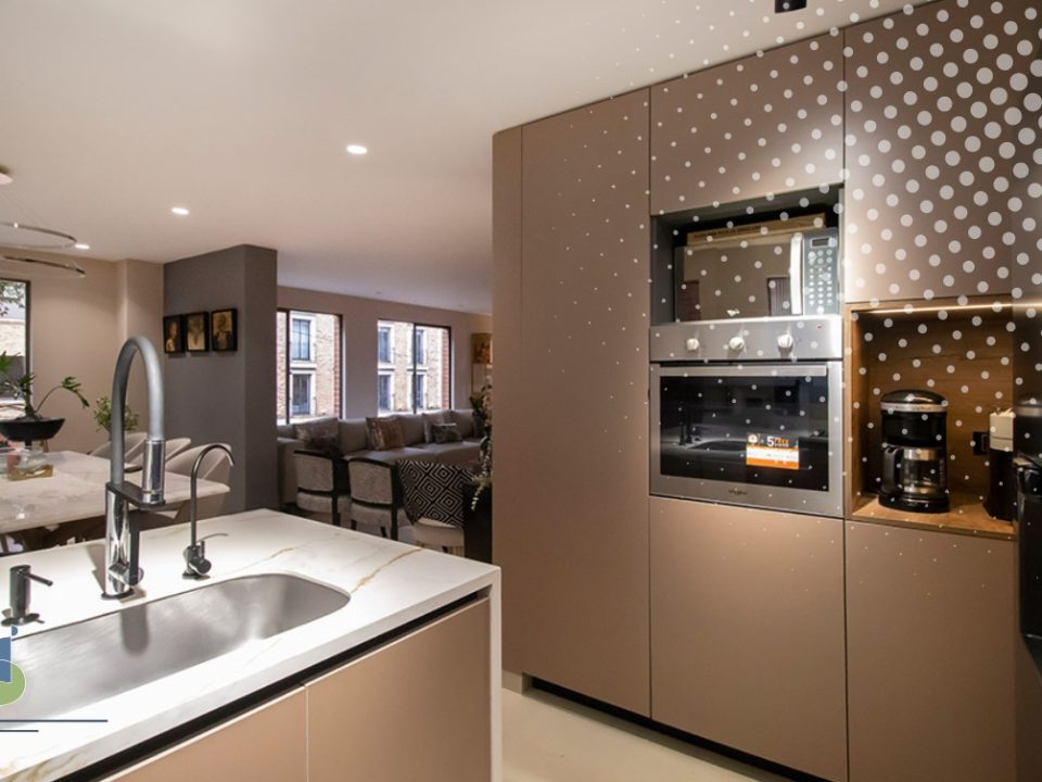 Cocina abierta con isla y lavaplatos conectada al comedor y la sala de un apartamento