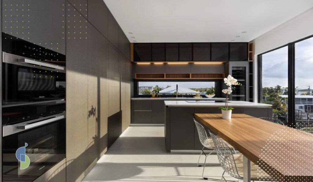Cocina minimalista con comedor integrado, destacando una gran ventana que aporta luz natural y amplitud. Los muebles integrados, fabricados con materiales de alta calidad, combinan funcionalidad y diseño elegante, creando un espacio armonioso y sofisticado