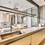 Cocina moderna con cerramiento de vidrio transparente entre sala y área de preparación de alimentos