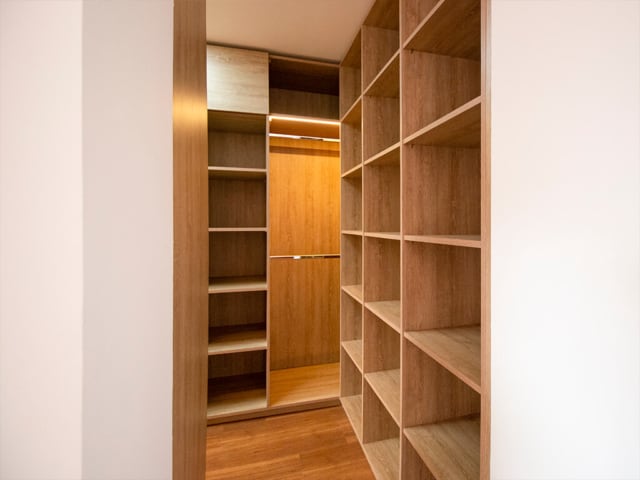 Walk-in closet práctico y elegante en madera, con cajones amplios y colgadero, iluminación LED