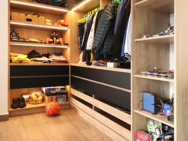 Walk-in closet práctico y elegante con vestidor, colores madera y negro con accesorios y herrajes importados, iluminación LED
