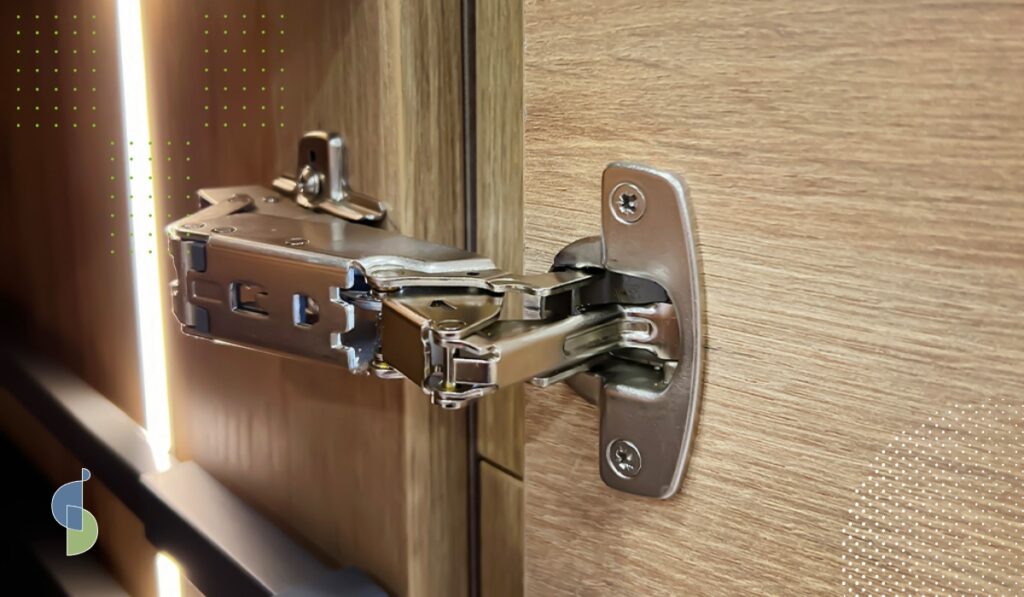 Detalle de bisagra Hettich instalada en la puerta de un mueble de cocina en madera