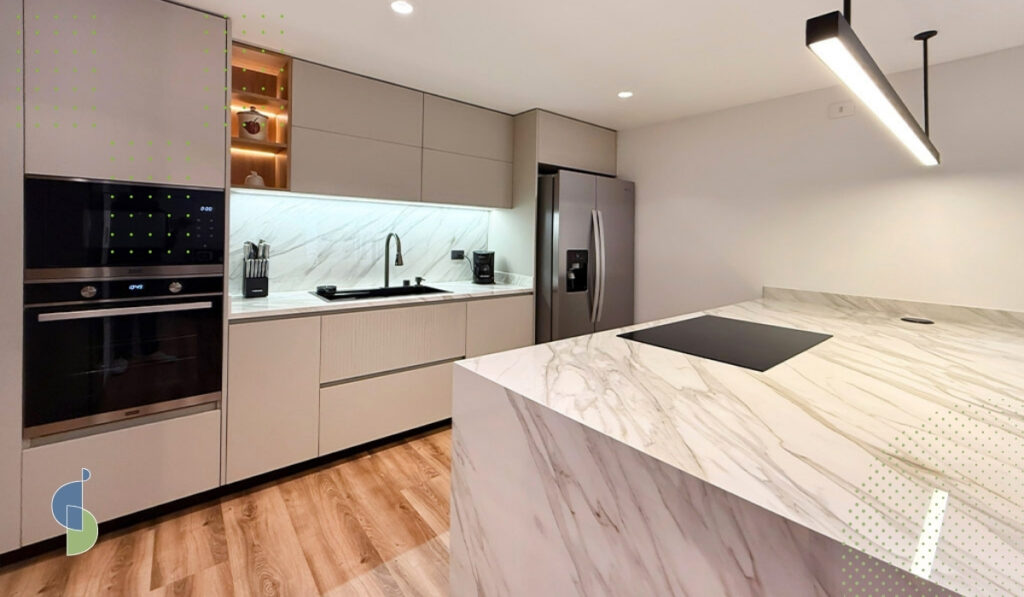 Cocina integral en acabado mate greige con mesón de mármol, isla en cascada y torre de horno empotrado